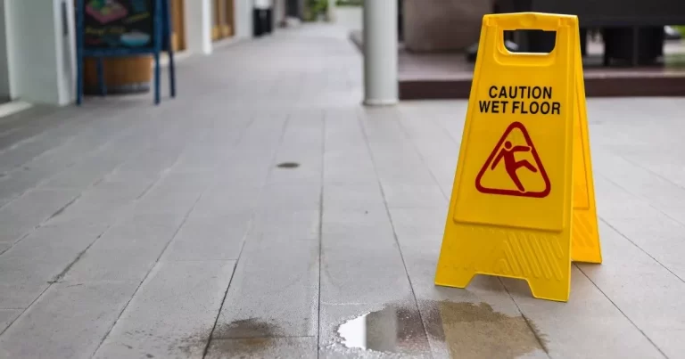 Wet floor in public area with yellow caution sign. Image represents public liability claims